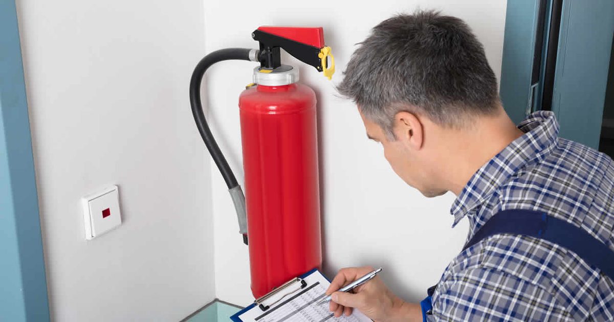 A technician inspecting a wall-mounted fire extinguisher